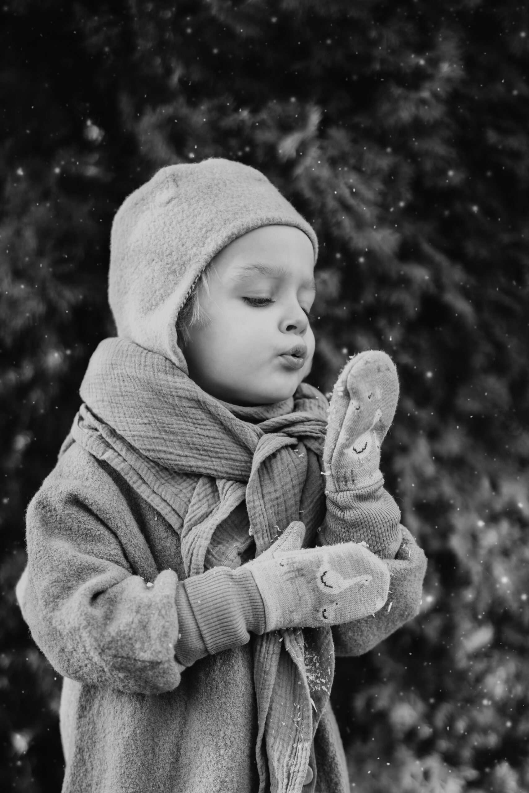 Kind pustet Schnee aus seinem Handschuh in Schwarz/Weiß